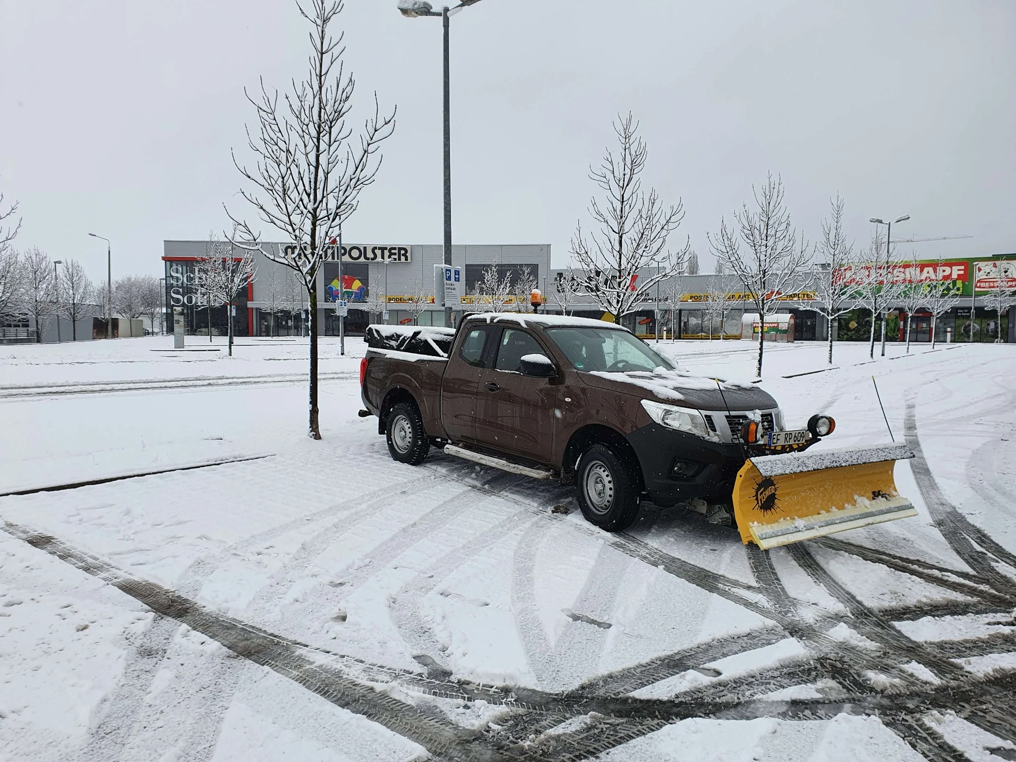 Pickup mit Schneeschild auf einer verschneiten Gewerbefläche
